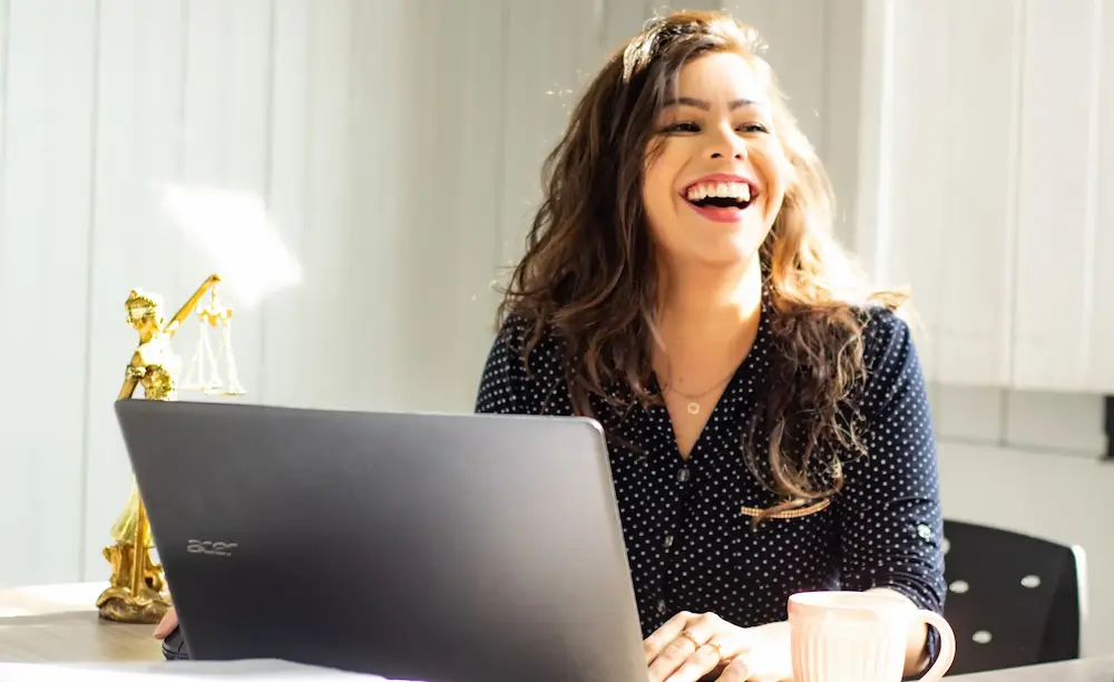 Femme riant qui se tient devant un ordinateur dans son entreprise